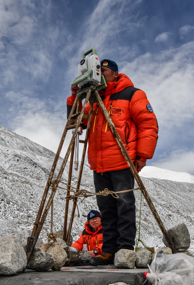 自然资源部第一大地测量队队员郑林（站立者）和武光伟在对珠峰峰顶进行交会观测（5月27日摄）。