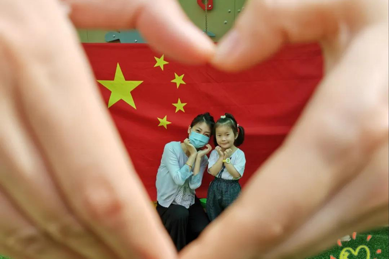 闵行区航华第三幼儿园学生与老师在五星红旗前留影。（来源：上海教育微信公众号）