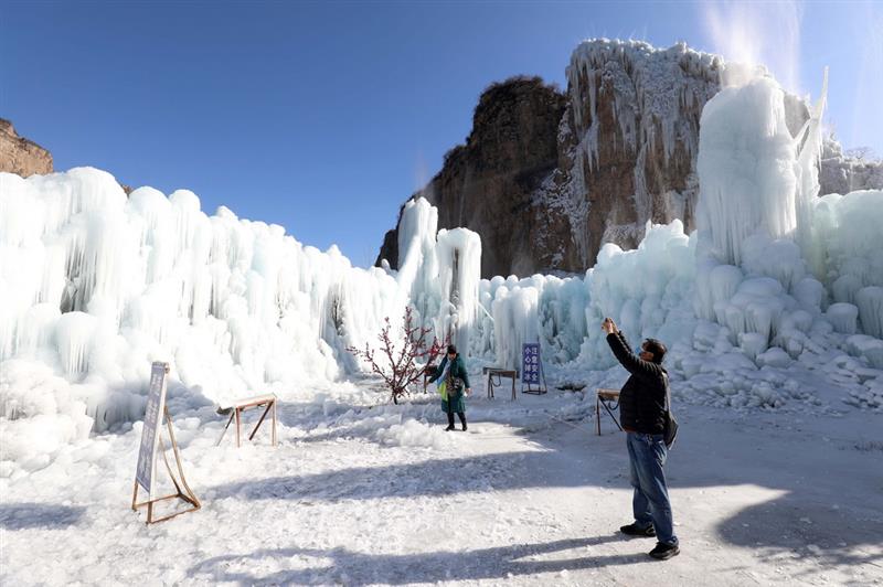 12月16日，在河北省平山县沕沕水景区，游客在冰瀑中拍照游玩。