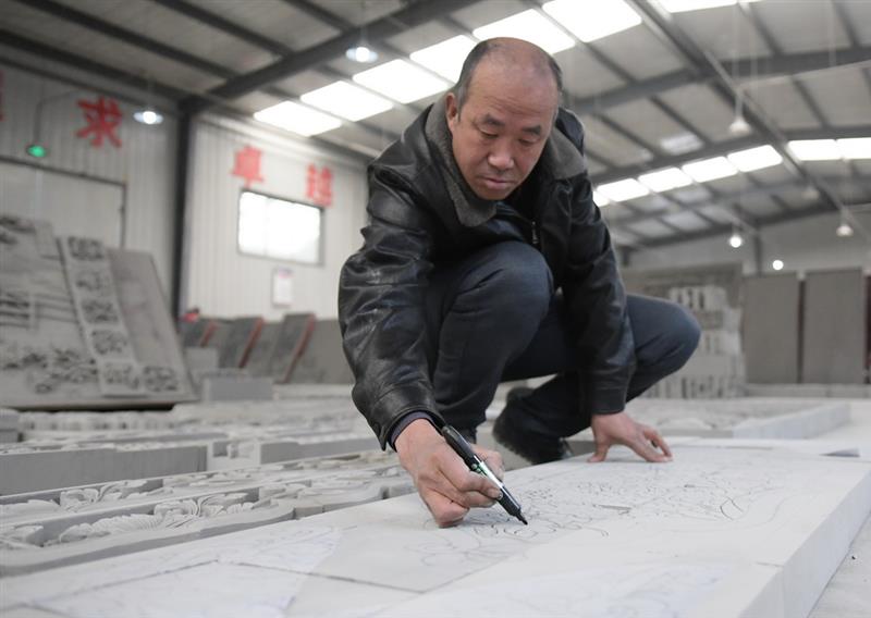 12月16日，在甘肃省临夏回族自治州临夏县一砖雕公司，工作人员在砖上绘制图案。