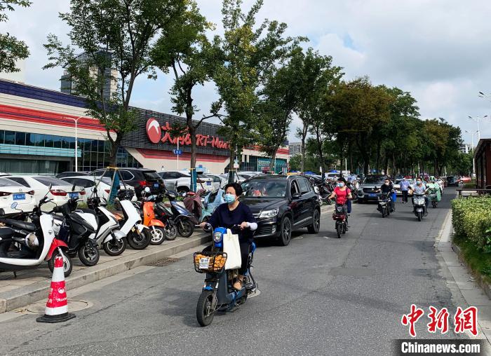 扬州一超市门口的人行道也停满了电动车。 崔佳明 摄 点击进入下一页