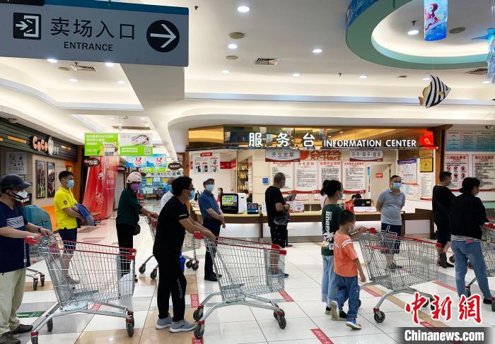 民众排着长长的队伍,在工作人员的指引下,等待进入超市购物。 崔佳明 摄 点击进入下一页